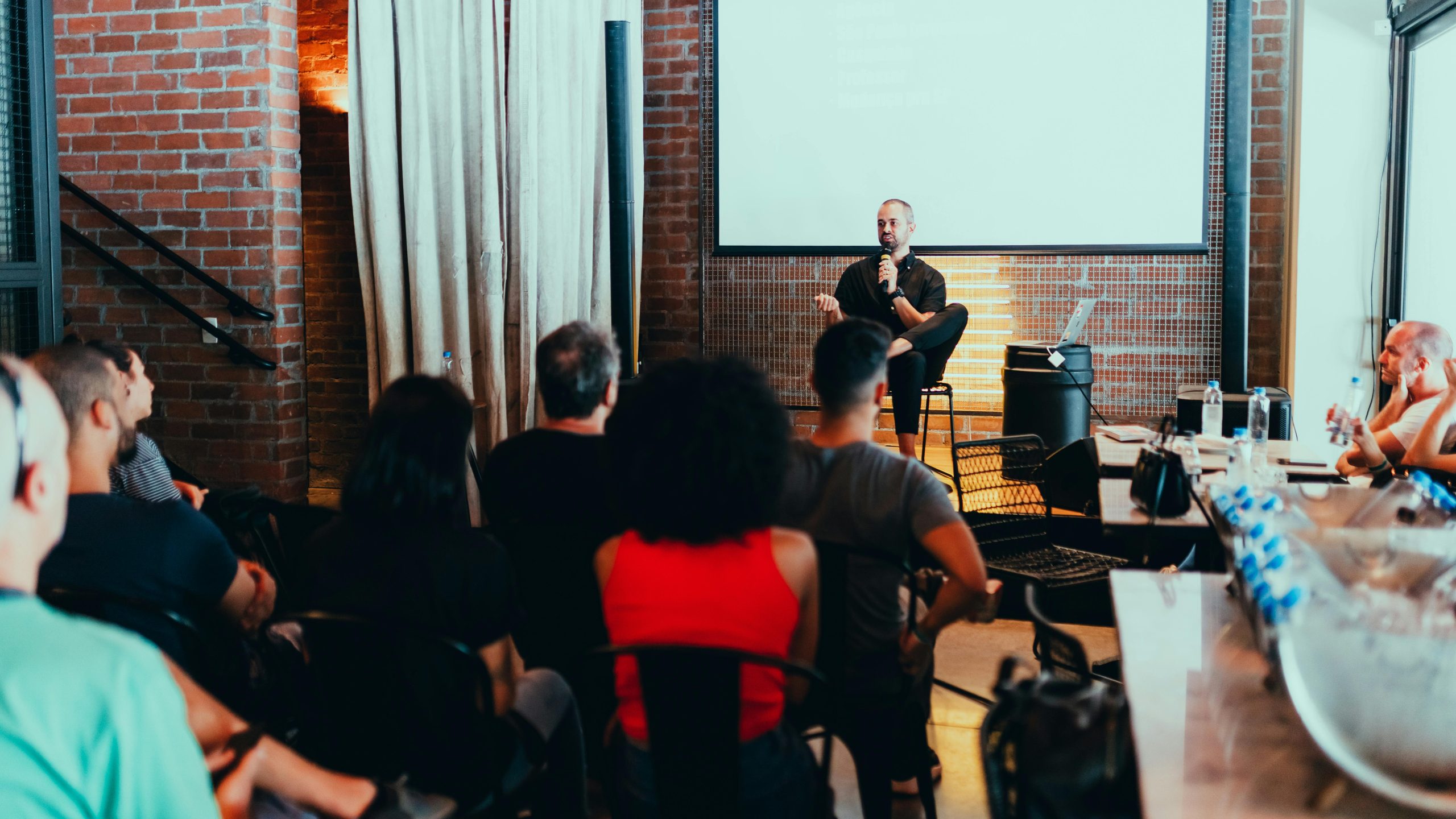 A dynamic seminar with a speaker engaging a diverse audience in a modern indoor setting.